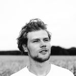 Black and white portrait of a man gazing away in a field.